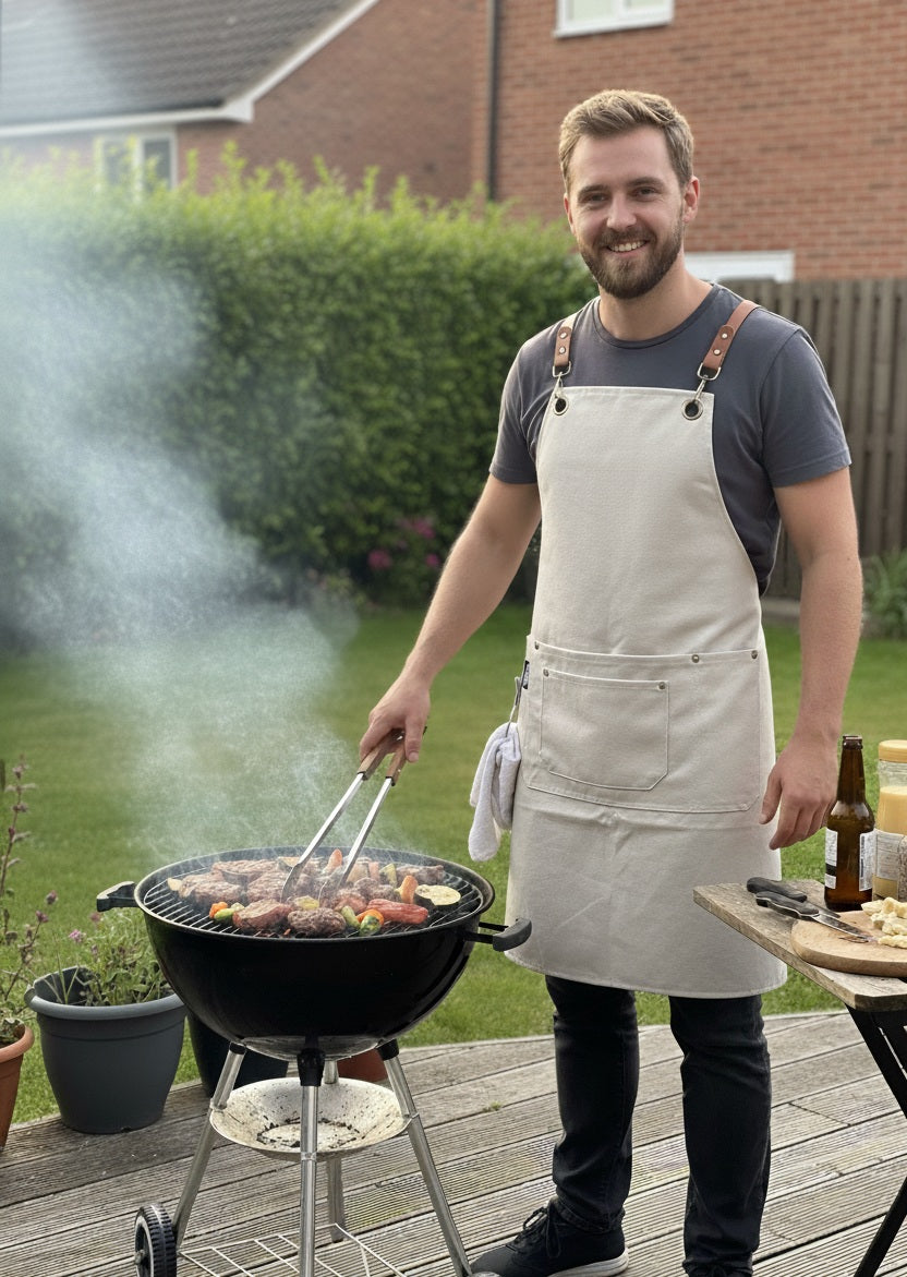 Waterproof cotton canvas apron in tan brown with adjustable neck strap and spacious front pockets, styled flat on rustic wooden background.