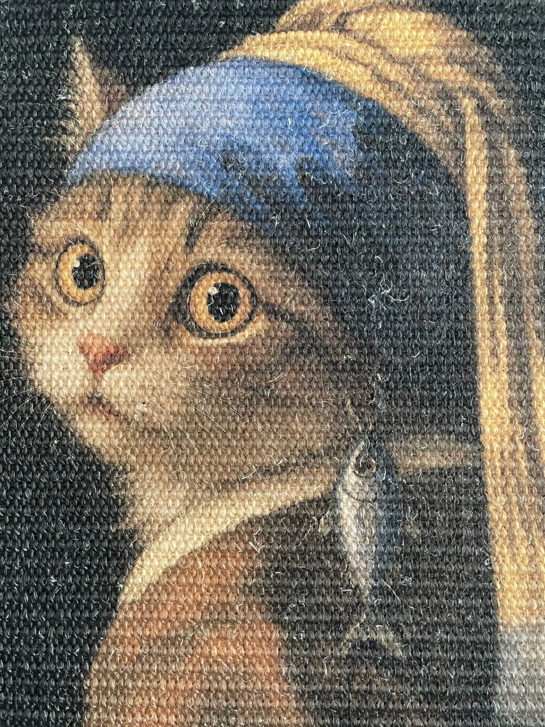 Decorative wall art with a cat wearing a tuna earring, titled 'Girl with a Tuna Earring', on a plain wall.