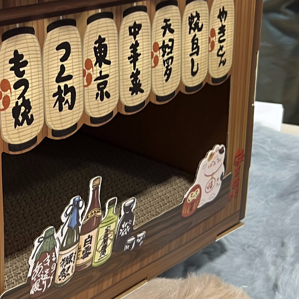 Maneki-neko lucky cat ornament beside sake bottle props on the wooden counter