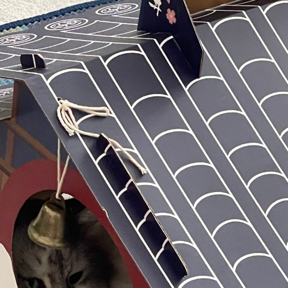 Navy cardboard roof with white tile pattern and the bell's cotton rope tucked under the eaves