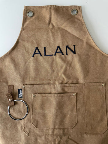 Tan brown cotton canvas apron with the name Alan embroidered on the bib in black thread | Whiskery Sour